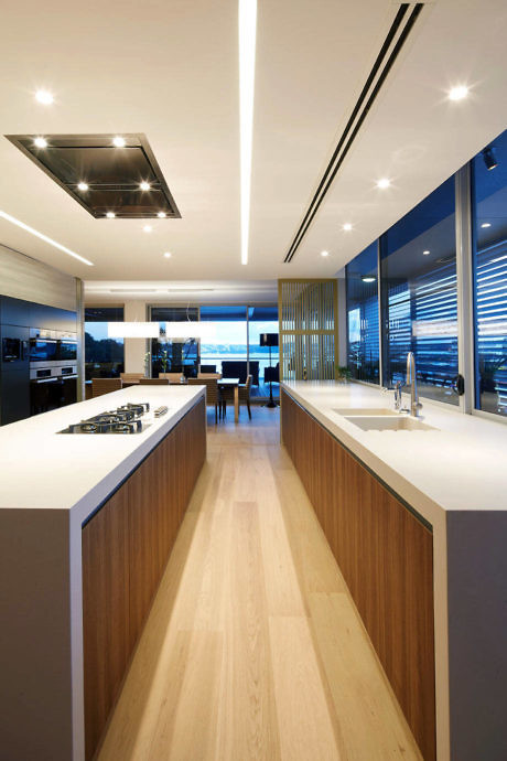 Sleek contemporary kitchen with linear lighting and ocean view.
