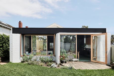 Modern home extension with glass doors, wooden deck, and landscaped garden.