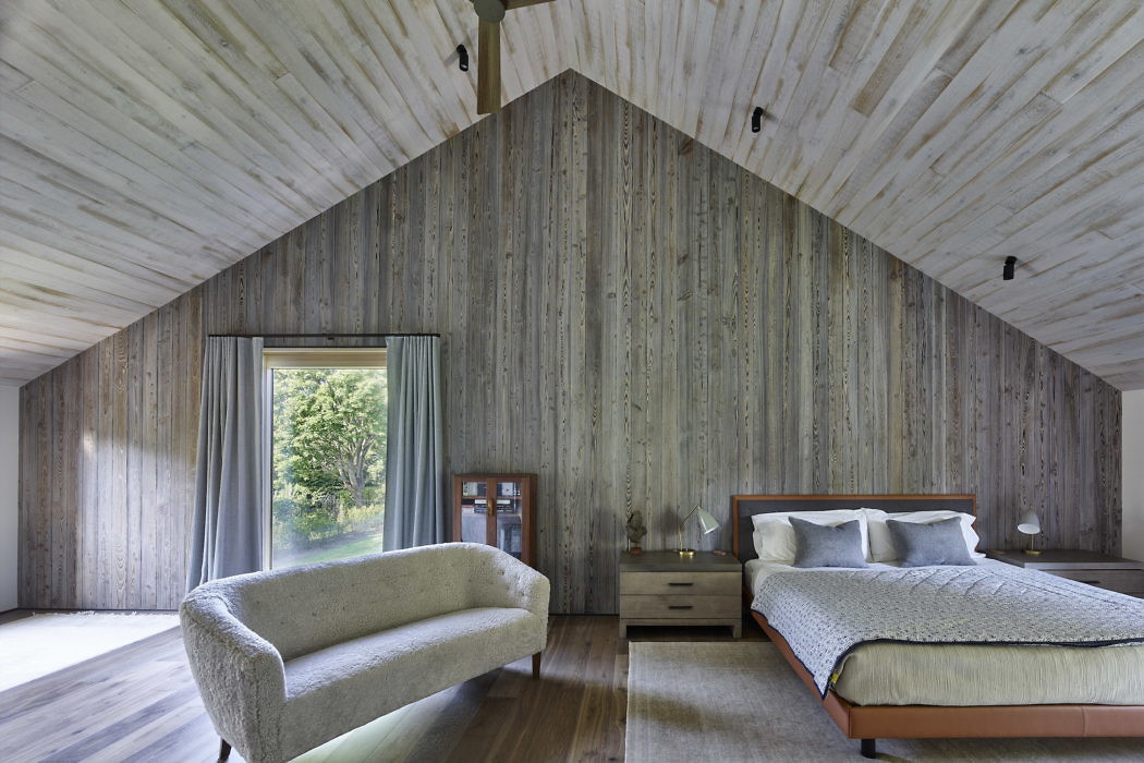 Wood-paneled attic bedroom with a sofa and bed.