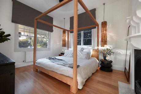 A stylish bedroom with a wooden four-poster bed and pendant lights.