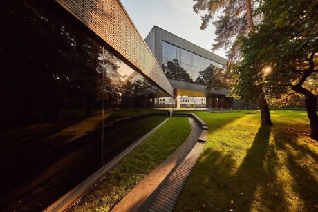 Contemporary building with glass facade and angular design among greenery.