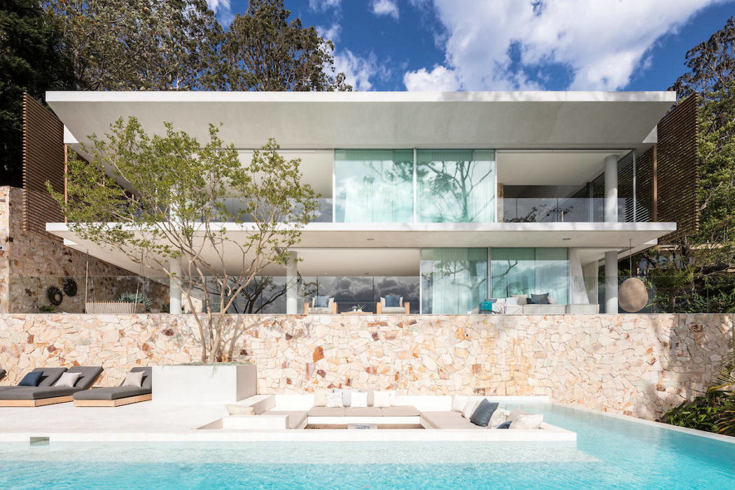 Contemporary home with glass facade, floating upper level, and pool.