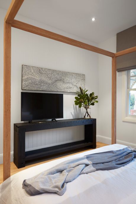 Modern bedroom with TV stand, wooden beams, and white walls.
