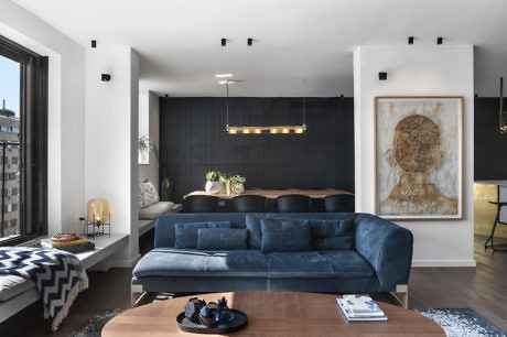Chic living room with blue sofa, wooden table, and abstract art.