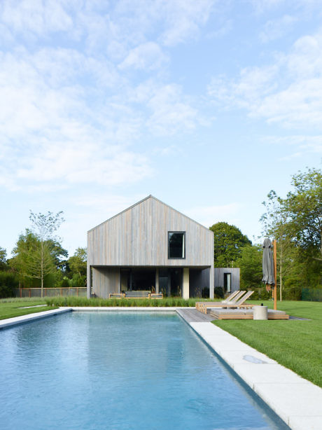 Modern house with a wooden facade and pool in a green lawn.