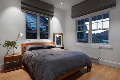 Contemporary bedroom with wooden bed frame and grey bedding.