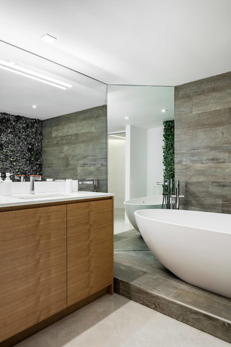Sleek bathroom with wood accents, a freestanding tub, and green