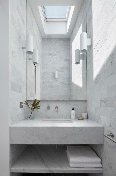Sleek marble bathroom with skylight and minimalist vanity.