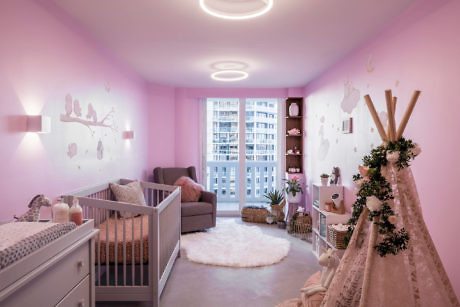 Cozy pink nursery room with crib, armchair, and teepee.