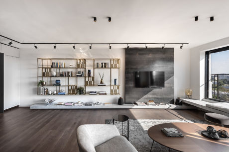 Modern living room with sleek furniture and shelving unit, large TV, and city