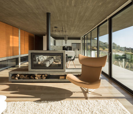 Sleek interior with fireplace, leather chair, and large windows.