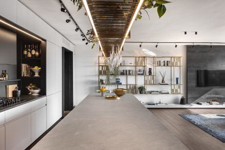 Sleek kitchen with long island, hanging plants, and open shelving.