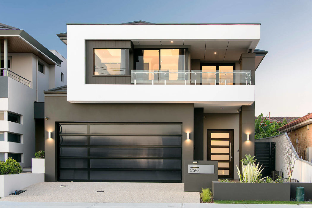 Modern two-story house with a large garage door and balcony.