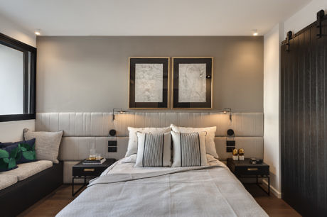 Modern bedroom with gray accents and artwork above bed.
