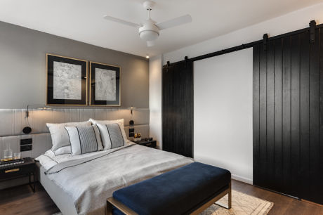 Contemporary bedroom with dark sliding barn door and elegant decor.