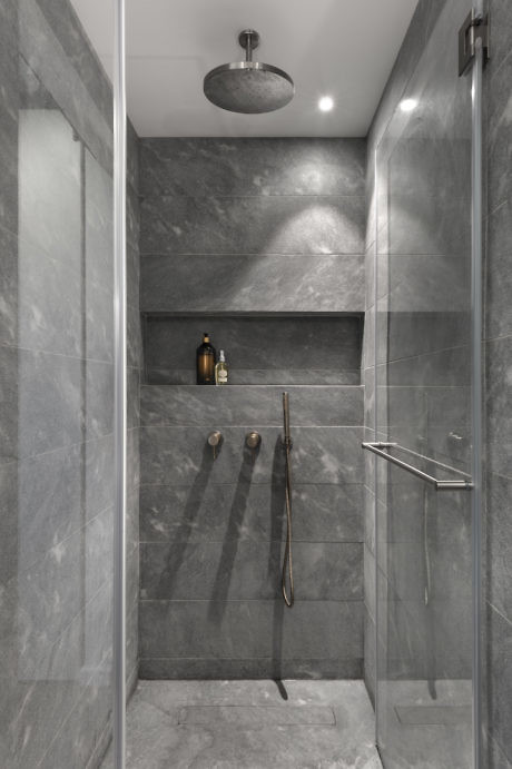 Sleek gray tiled walk-in shower with recessed shelf and rainfall showerhead