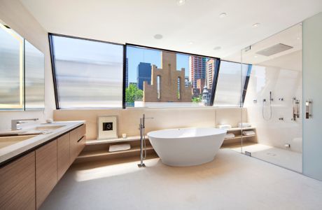 Modern bathroom with a freestanding tub and city view through large windows.