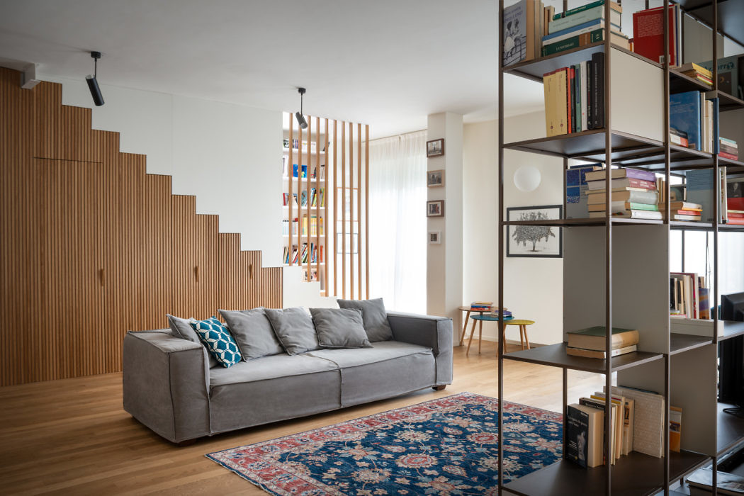 Contemporary living room with wooden staircase and bookshelf-divider.