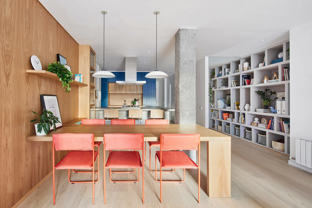 Modern kitchen with wooden dining set, blue accents, and bookshelf.