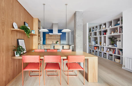 Modern kitchen with wooden dining set, blue accents, and bookshelf.