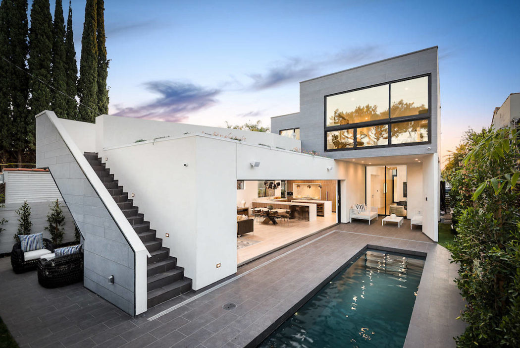 Modern two-story house with large windows, pool, and outdoor staircase.