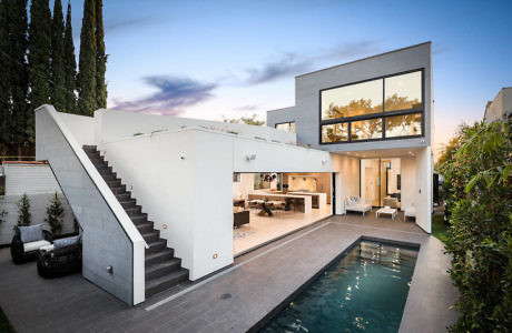 Modern two-story house with large windows, pool, and outdoor staircase.