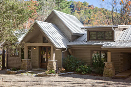 Modern house with metal roof surrounded by autumn trees.