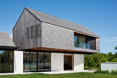 Contemporary house with wooden siding and large windows.