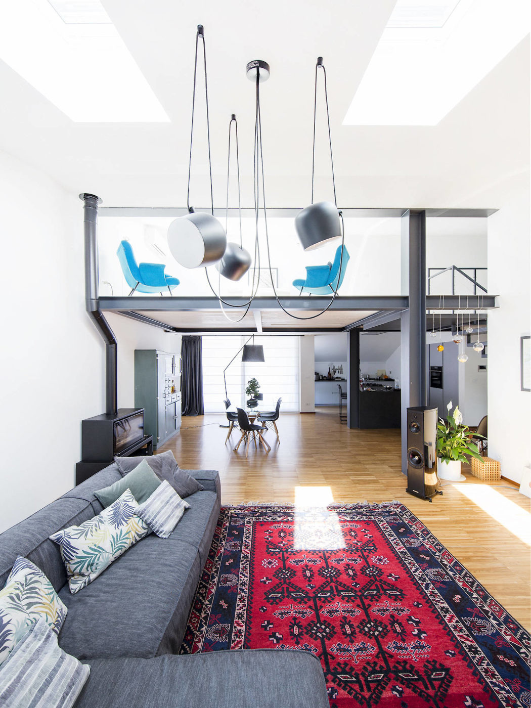 Modern living room with a loft, hanging chairs, sectional sofa, and red pattern