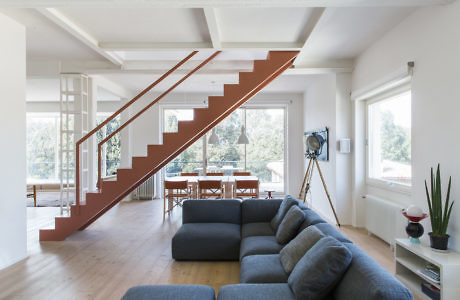 Bright minimalist living space with a bold red staircase.