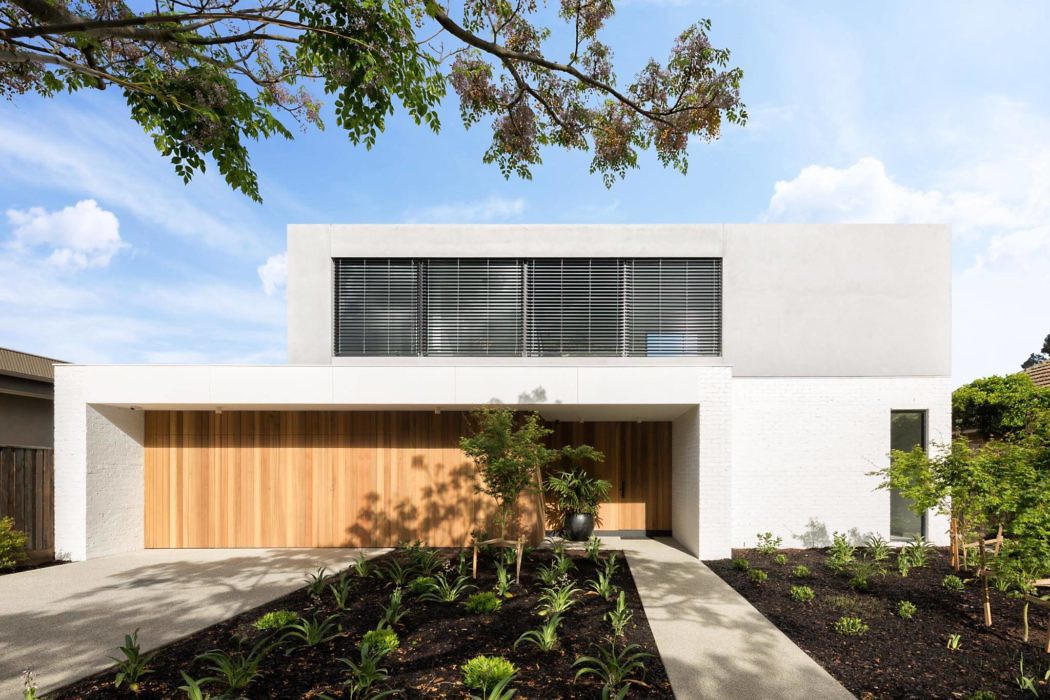 Contemporary white house with wooden garage door and garden.