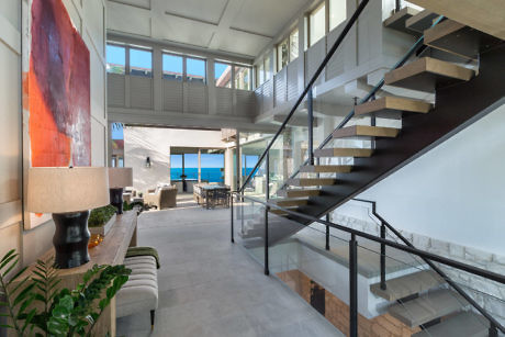 Modern home interior with floating staircase and ocean view.