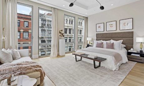 Chic urban bedroom with large windows and neutral tones.