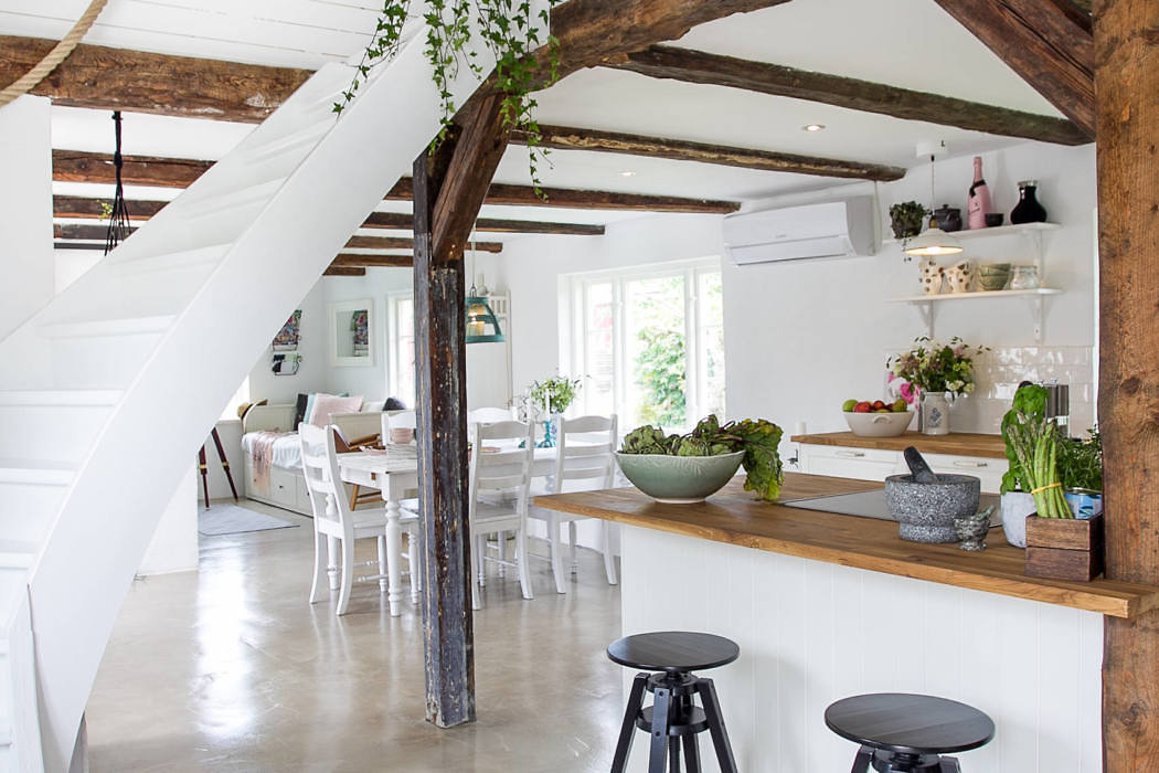 Modern rustic kitchen with white decor, exposed beams, and a spiral staircase.