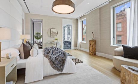 Elegant bedroom with neutral tones, large windows, and plush textiles.