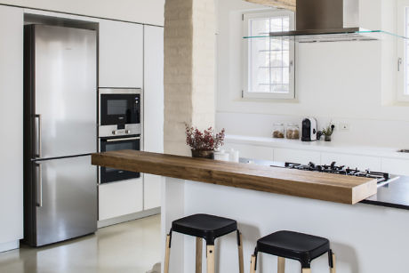 Minimalistic kitchen with white cabinetry and wooden countertop.