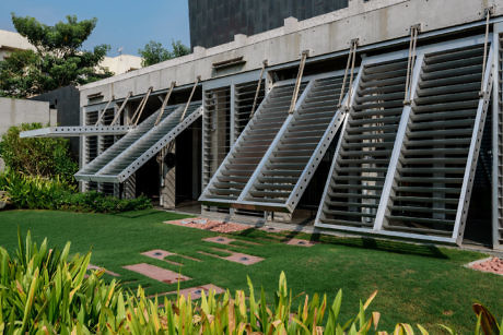 Contemporary building with angled louvers and landscaped garden.