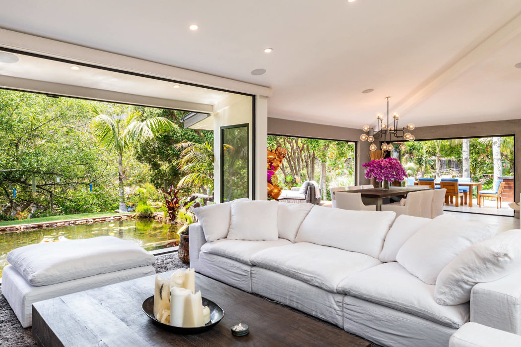 Bright living room with large sofa, sliding glass doors, and view of lush outdoor