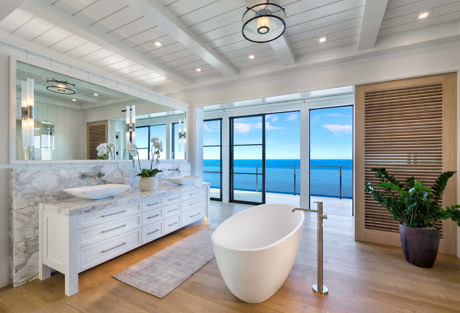 Elegant coastal bathroom with ocean view, freestanding tub, and marble vanity