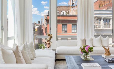 Modern living room with white sofa, large windows, and city view.
