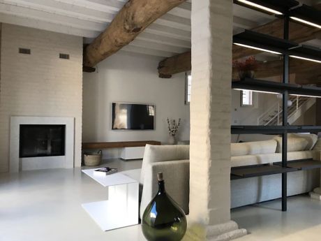 Modern living room with exposed beams, fireplace, and minimalist furniture.