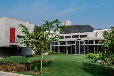 Modern building with textured facade, red accent, and landscaped lawn.