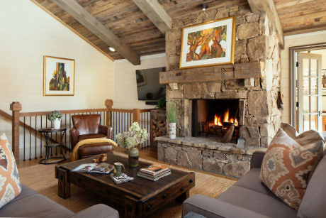 Cozy living room with a stone fireplace, wooden beams, and comfortable seating.