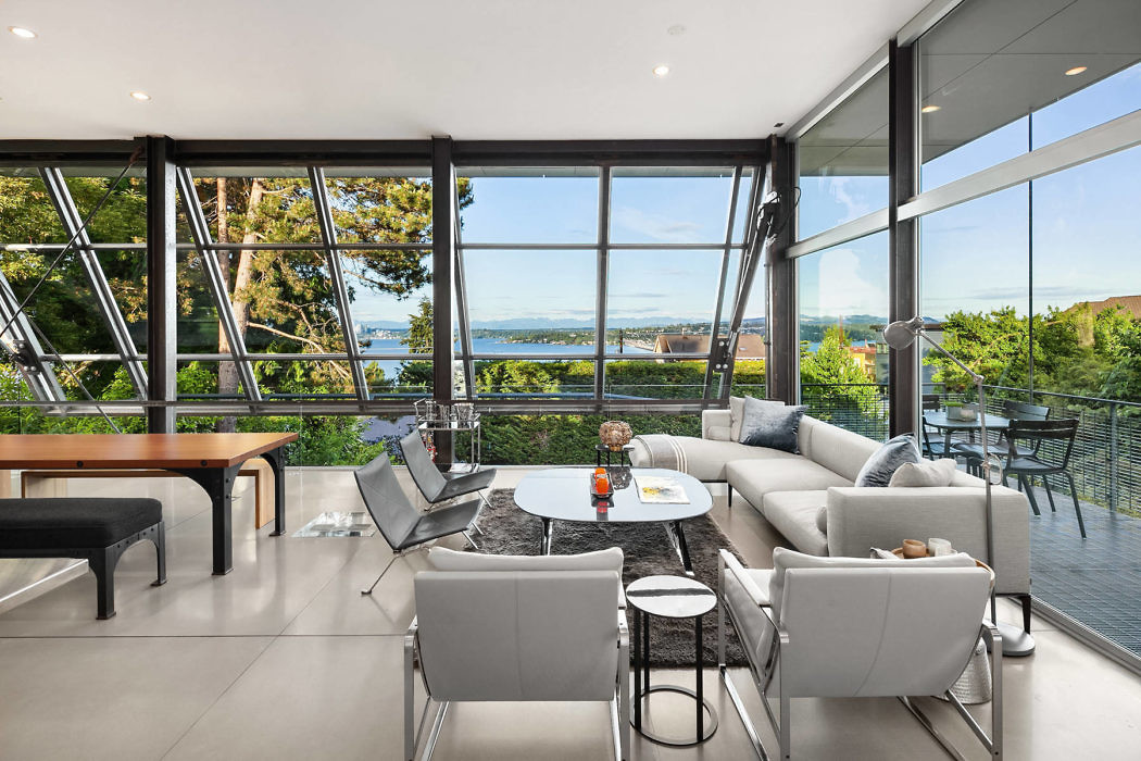 Contemporary living room with large windows and waterfront view.