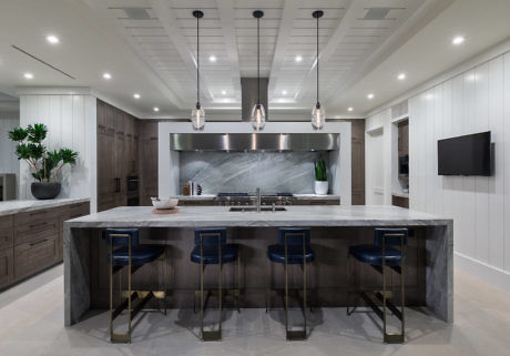Chic kitchen with marble island, blue stools, and pendant lighting.