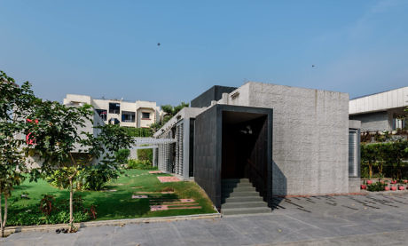 Contemporary building with textured concrete and open lawn.