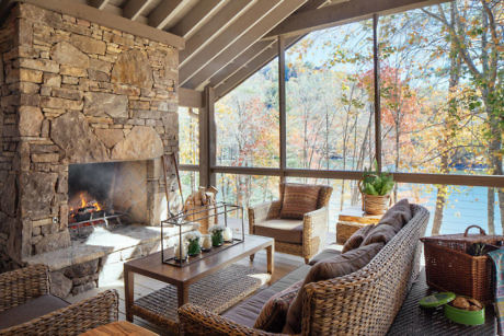 Cozy lakeside porch with stone fireplace and autumn view.