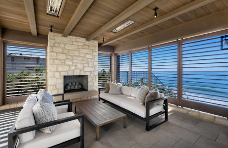 Coastal-style covered patio with a fireplace and ocean view.