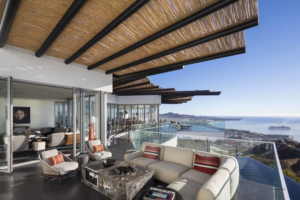 Contemporary living room with ocean view, glass walls, and exposed wooden ceiling.