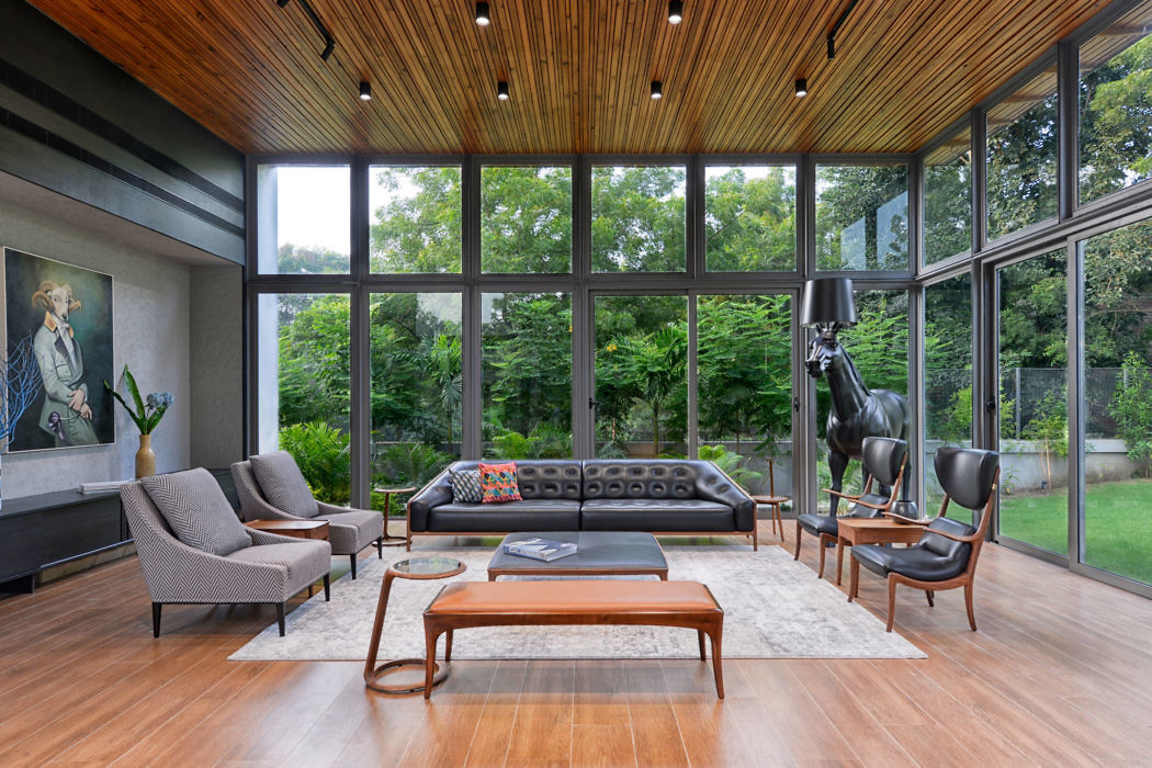 Modern living room with large windows, wooden ceiling, and stylish furniture.